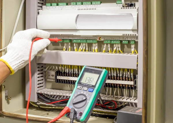 Electrical engineer tests the operation of the electric control cabinet on a regular basis for maintenance.