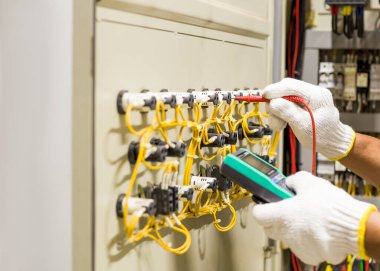 Elektrik mühendisi elektrik kontrol kabinesinin bakımını düzenli olarak test ediyor.