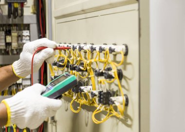 Elektrik mühendisi elektrik kontrol kabinesinin bakımını düzenli olarak test ediyor.