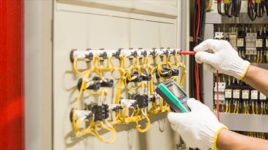 Elektrik mühendisi elektrik kontrol kabinesinin bakımını düzenli olarak test ediyor.