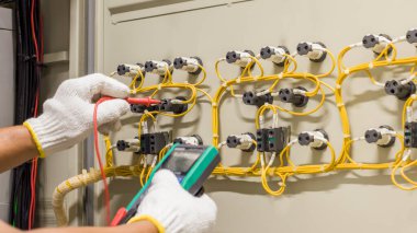 Elektrik mühendisi elektrik kontrol kabinesinin bakımını düzenli olarak test ediyor.