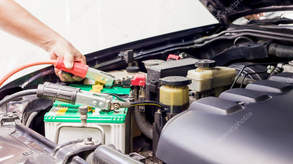 Close up Charging car battery with electricity through jumper cables.