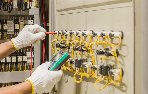 Electrical engineer tests the operation of the electric control cabinet on a regular basis for maintenance.