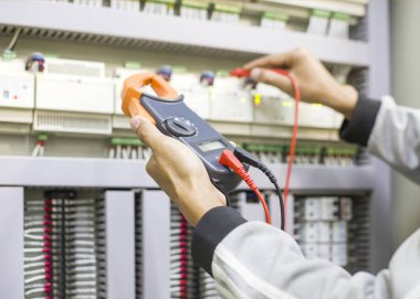 Elektrik mühendisi elektrik kontrol kabinesinin bakımını düzenli olarak test ediyor.