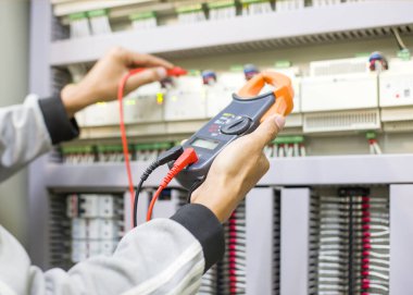 Elektrik mühendisi elektrik kontrol kabinesinin bakımını düzenli olarak test ediyor.