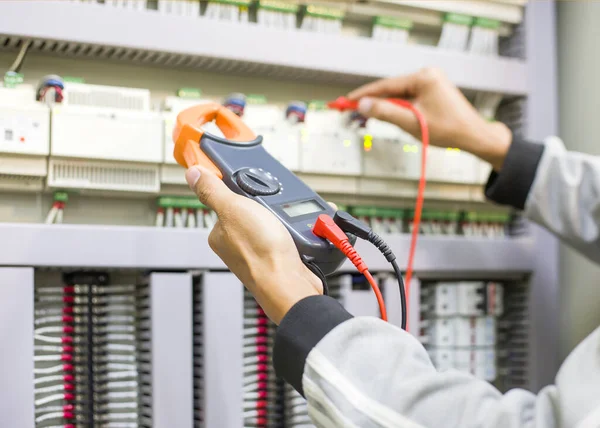 Electrical engineer tests the operation of the electric control cabinet on a regular basis for maintenance.