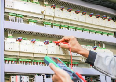 Elektrik mühendisi elektrik kontrol kabinesinin bakımını düzenli olarak test ediyor.