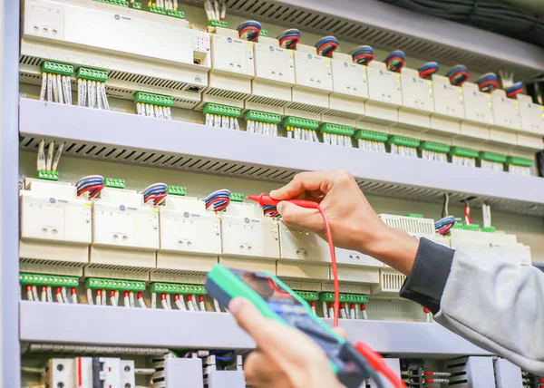 Elektrik mühendisi elektrik kontrol kabinesinin bakımını düzenli olarak test ediyor.