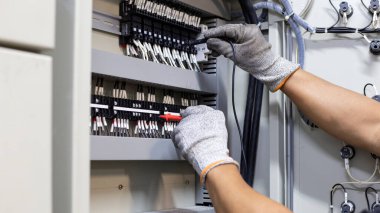 Elektrik mühendisi elektrik kontrol kabinesinin bakımını düzenli olarak test ediyor.