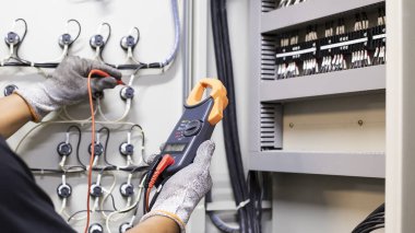 Elektrik mühendisi elektrik kontrol kabinesinin bakımını düzenli olarak test ediyor.