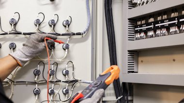 Elektrik mühendisi elektrik kontrol kabinesinin bakımını düzenli olarak test ediyor.