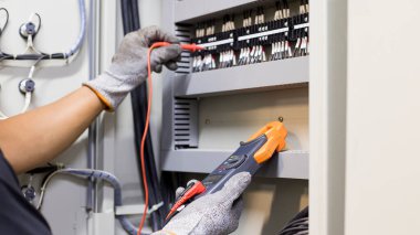 Elektrik mühendisi elektrik kontrol kabinesinin bakımını düzenli olarak test ediyor.