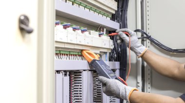 Elektrik mühendisi elektrik kontrol kabinesinin bakımını düzenli olarak test ediyor.