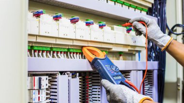 Elektrik mühendisi elektrik kontrol kabinesinin bakımını düzenli olarak test ediyor.