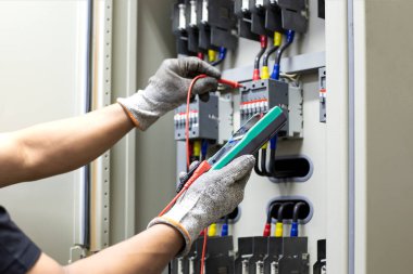 Elektrik mühendisi elektrik kontrol kabinesinin bakımını düzenli olarak test ediyor.