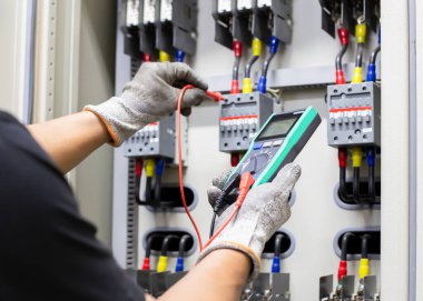 Elektrik mühendisi elektrik kontrol kabinesinin bakımını düzenli olarak test ediyor.