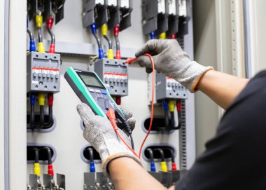 Elektrik mühendisi elektrik kontrol kabinesinin bakımını düzenli olarak test ediyor.