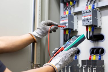 Elektrik mühendisi elektrik kontrol kabinesinin bakımını düzenli olarak test ediyor.