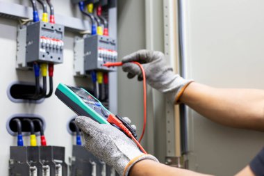 Elektrik mühendisi elektrik kontrol kabinesinin bakımını düzenli olarak test ediyor.
