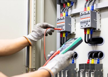 Elektrik mühendisi elektrik kontrol kabinesinin bakımını düzenli olarak test ediyor.