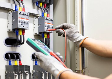 Elektrik mühendisi elektrik kontrol kabinesinin bakımını düzenli olarak test ediyor.