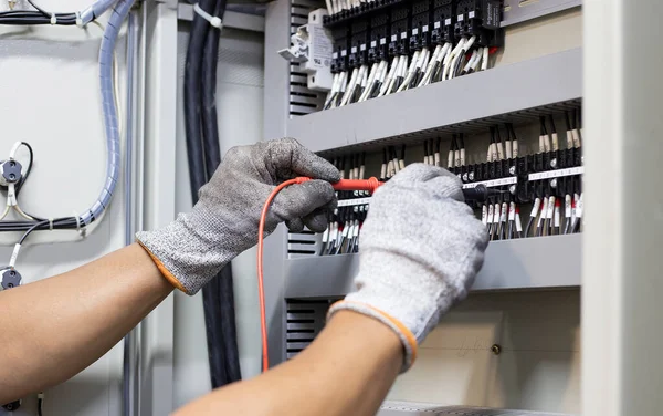 Electrical engineer tests the operation of the electric control cabinet on a regular basis for maintenance.