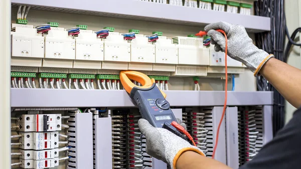 Electrical engineer tests the operation of the electric control cabinet on a regular basis for maintenance.