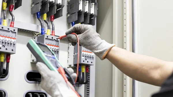 Electrical engineer tests the operation of the electric control cabinet on a regular basis for maintenance.