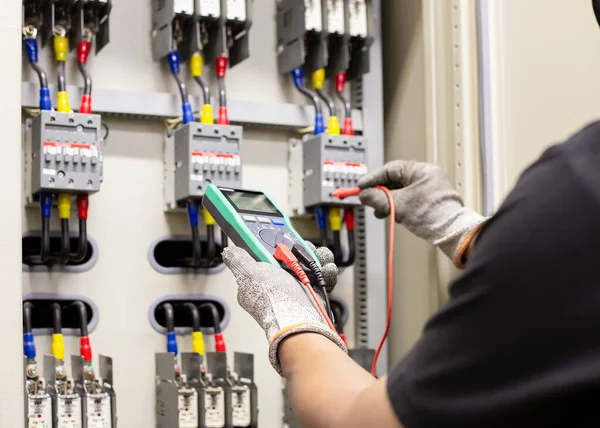 Electrical engineer tests the operation of the electric control cabinet on a regular basis for maintenance.