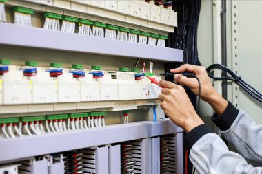 Elektrik mühendisi elektrik kontrol kabinesinin bakımını düzenli olarak test ediyor.