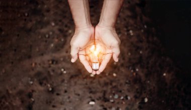 El ele tutuşmak ampul, doğal enerji ve dünya konseptini sevmek.