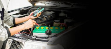 Bir teknisyen araba aküsünü kontrol ediyor..;