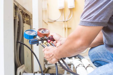 Hava tamircisi endüstriyel klimaları doldurmak için ölçüm aletleri kullanıyor..