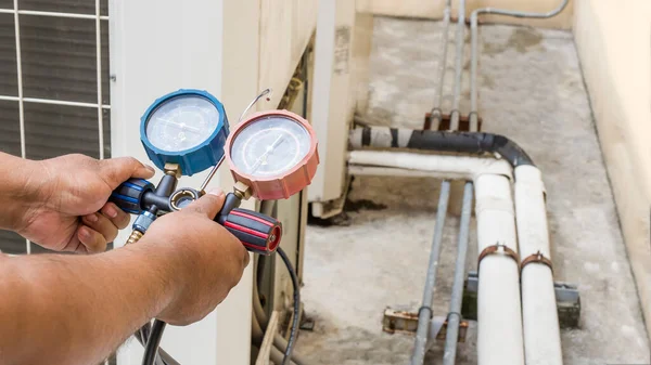 Hava tamircisi endüstriyel klimaları doldurmak için ölçüm aletleri kullanıyor..
