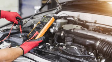 Bir teknisyen araba aküsünü kontrol ediyor..