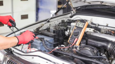 Bir teknisyen araba aküsünü kontrol ediyor..