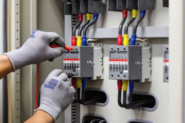 Electrical engineer checking the operation of electrical control cabinet, maintenance concept.