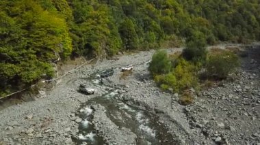 Off Road araçları Vahşi Dağ Nehri 'ni geçiyor. SUV arabalarının hava görüntüsü.
