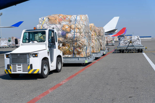 Cargo service and airport baggage vehicle. Airport vehicle transporting cargo to airplane on runway