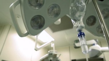 Arka planda bulanık ilaç damlası ve yoğun bakım ünitesinde de cerrahi ışık sistemi var. Ameliyathanede tıbbi aletler var..