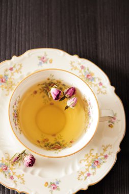 Vintage fincan çay ile siyah arka plan üzerine gül goncası