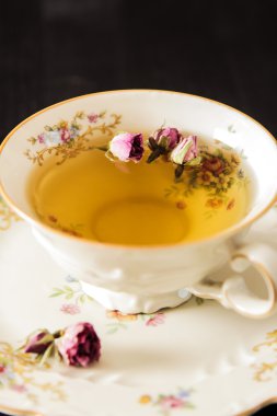 Vintage fincan çay ile siyah arka plan üzerine gül goncası