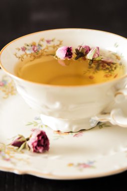 Vintage fincan çay ile siyah arka plan üzerine gül goncası