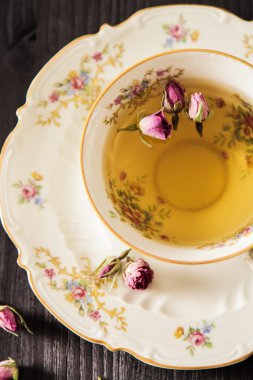 Vintage fincan çay ile siyah arka plan üzerine gül goncası