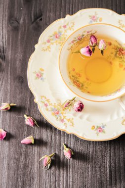 Vintage fincan çay ile siyah arka plan üzerine gül goncası