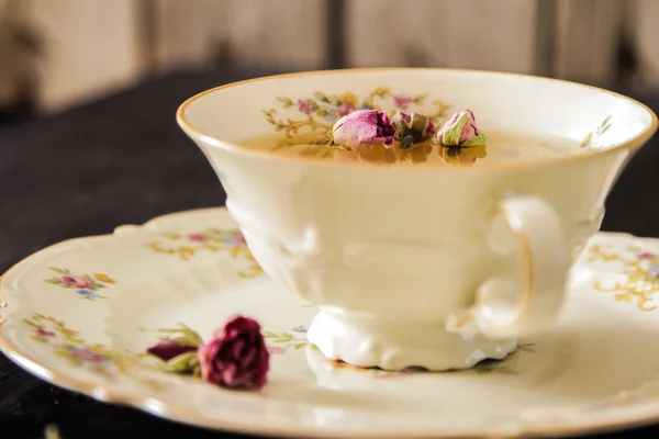 Vintage-Tasse Tee mit Rosenblüten, auf schwarzem Hintergrund — Stockfoto