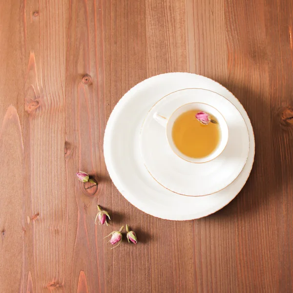 Vintage Tasse Tee mit Rosenblüten, auf braunem Hintergrund — Stockfoto