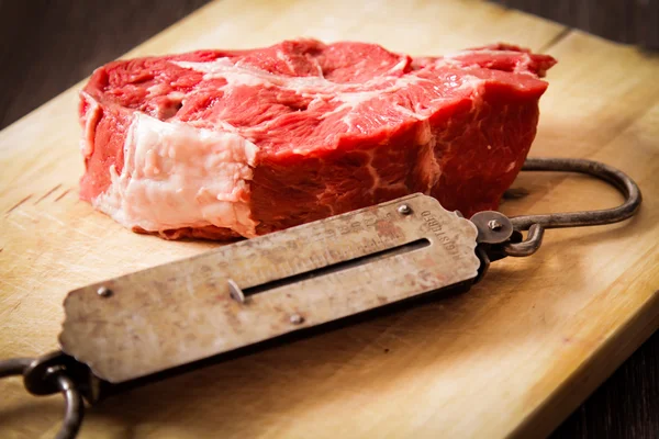 Piece of raw meat with hand weights old — Stock Photo, Image