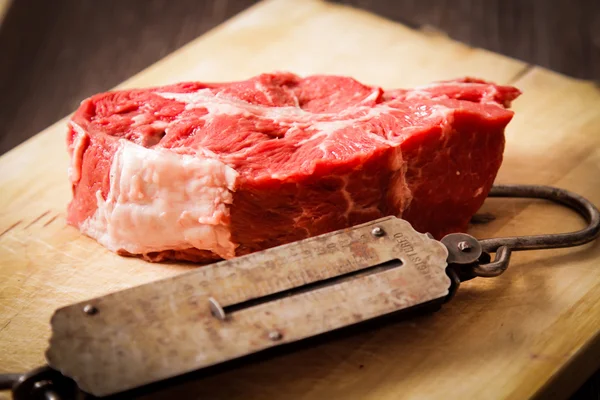 Piece of raw meat with hand weights old — Stock Photo, Image