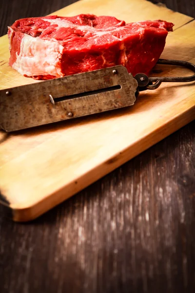 Piece of raw meat with hand weights old — Stock Photo, Image